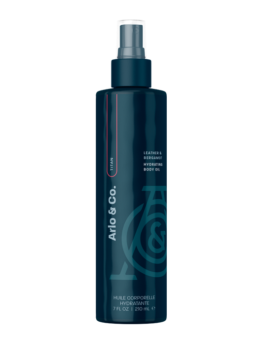 Dark blue bottle of leather and bergamot hydrating body oil with spray nozzle, 210ml