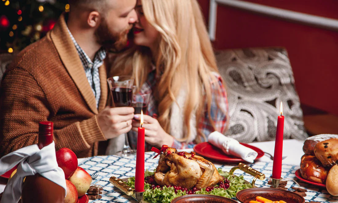 Romantic couple enjoying wine at festive dinner table with roast chicken and holiday candles