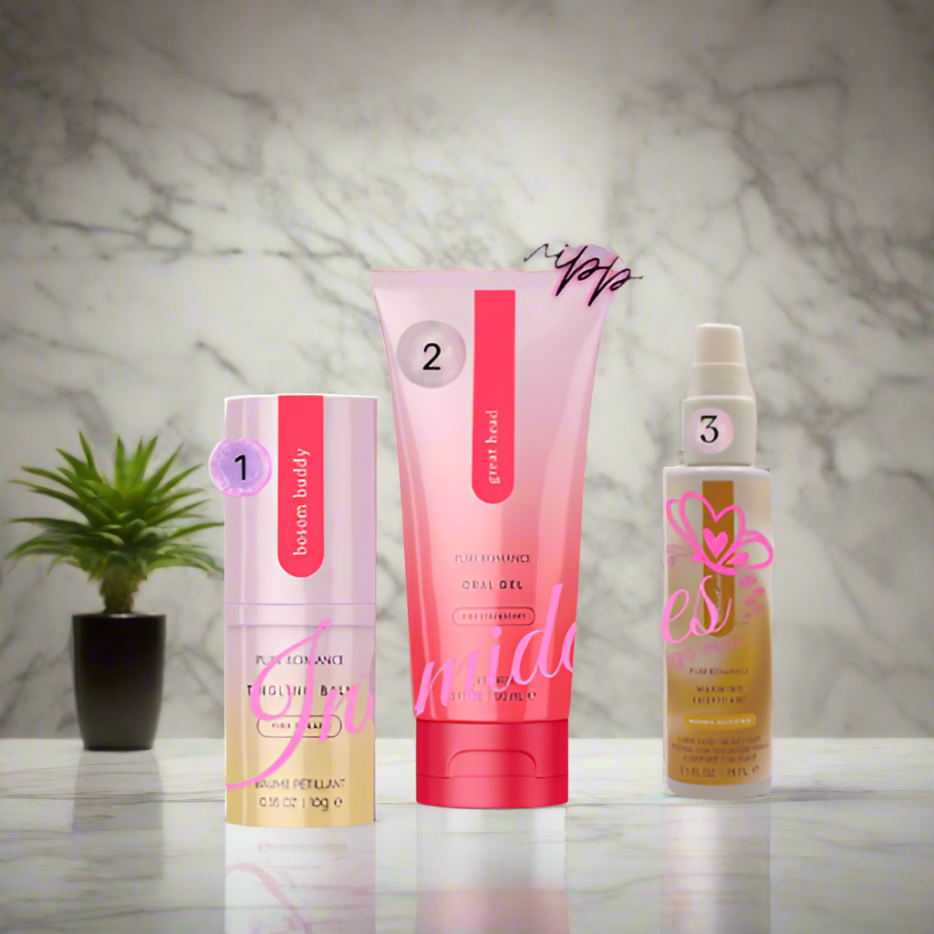 Three sexual wellness products in pink packaging on a marble counter with a small potted plant.