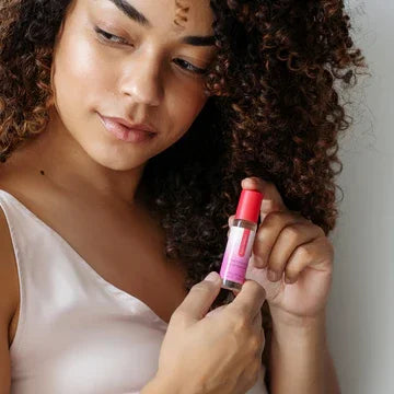 Woman holding sensual massage oil bottle with pink label, skincare and wellness product