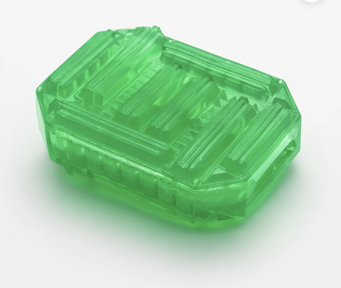 Green translucent soap bar with geometric design on white background, skincare product