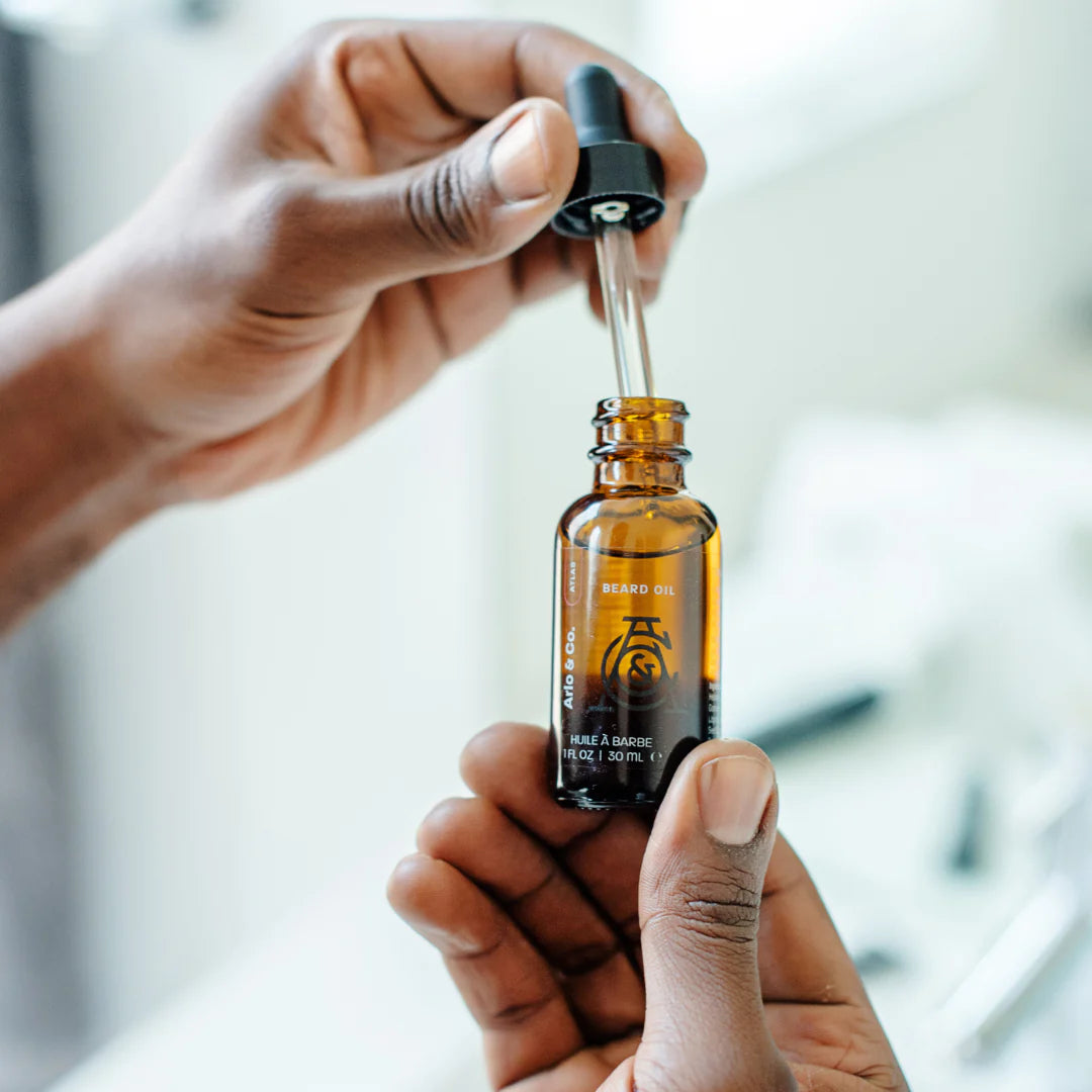 Hand holding dropper with beard oil for grooming and skin care