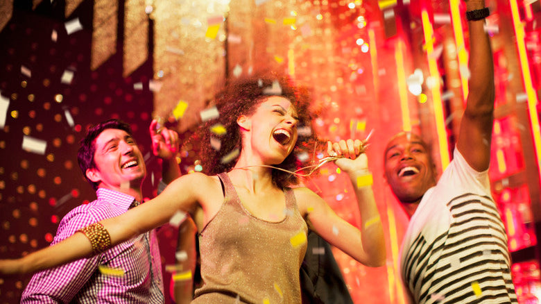 Young adults celebrating at a vibrant party with confetti and colorful lights