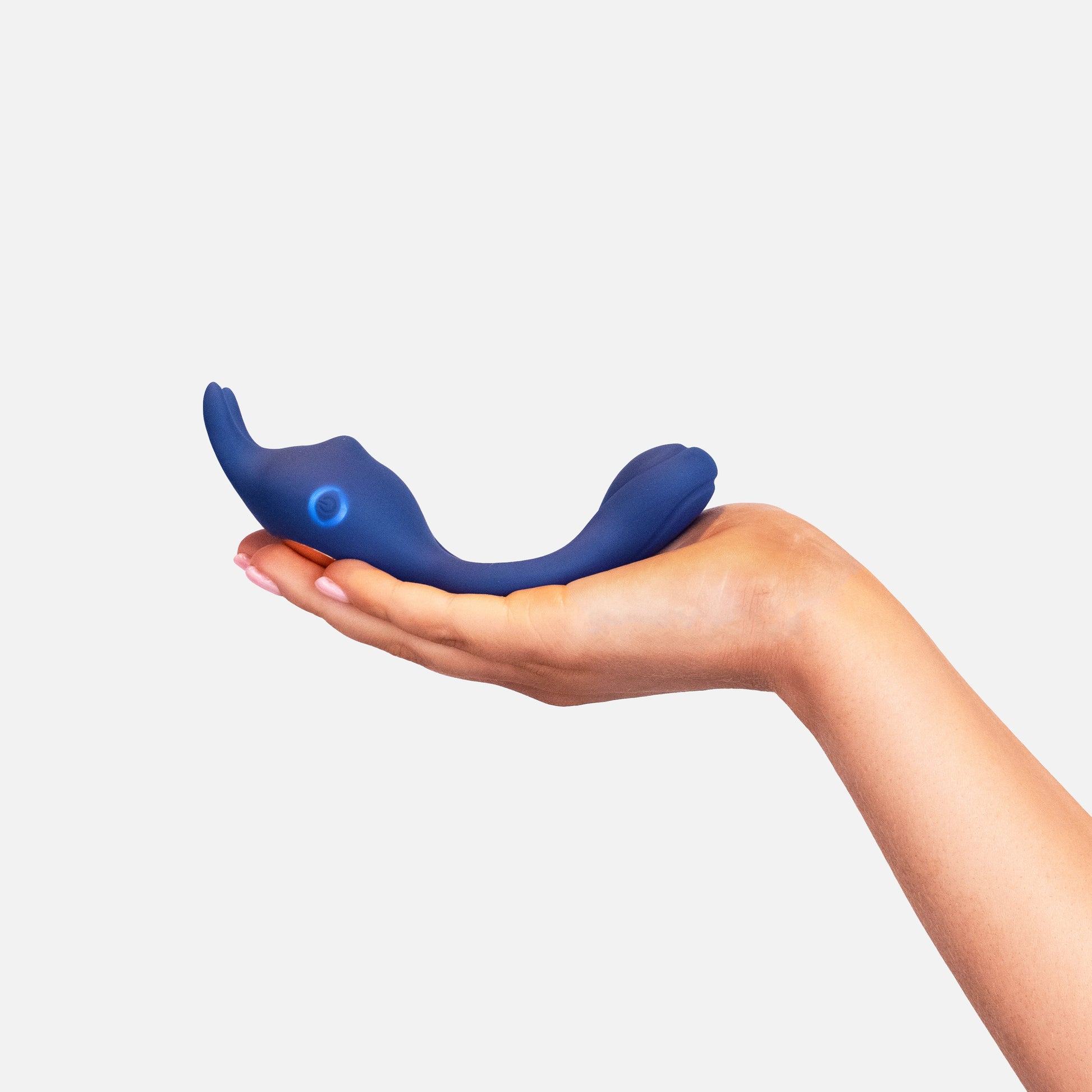 Hand holding blue silicone wellness massager against white background