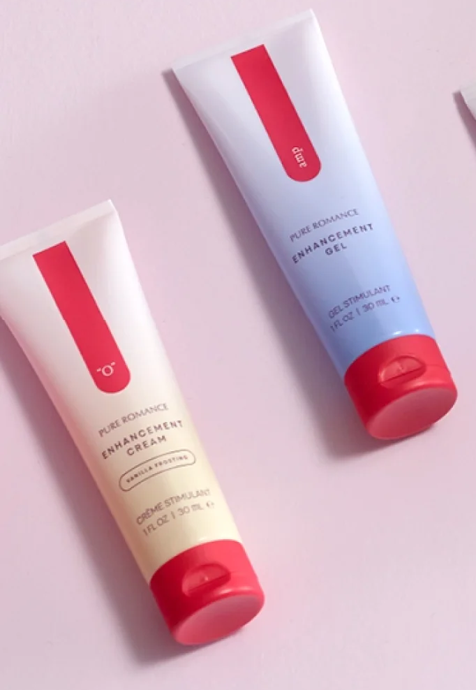 Two tubes of enhancement cream and gel for intimacy, on a light pink background.