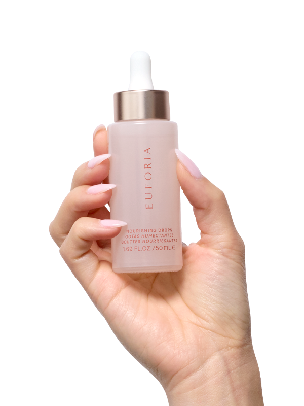 Hand holding Euforia nourishing drops skincare serum bottle with dropper