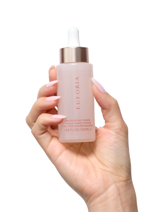 Hand holding Euforia nourishing drops skincare serum bottle with dropper