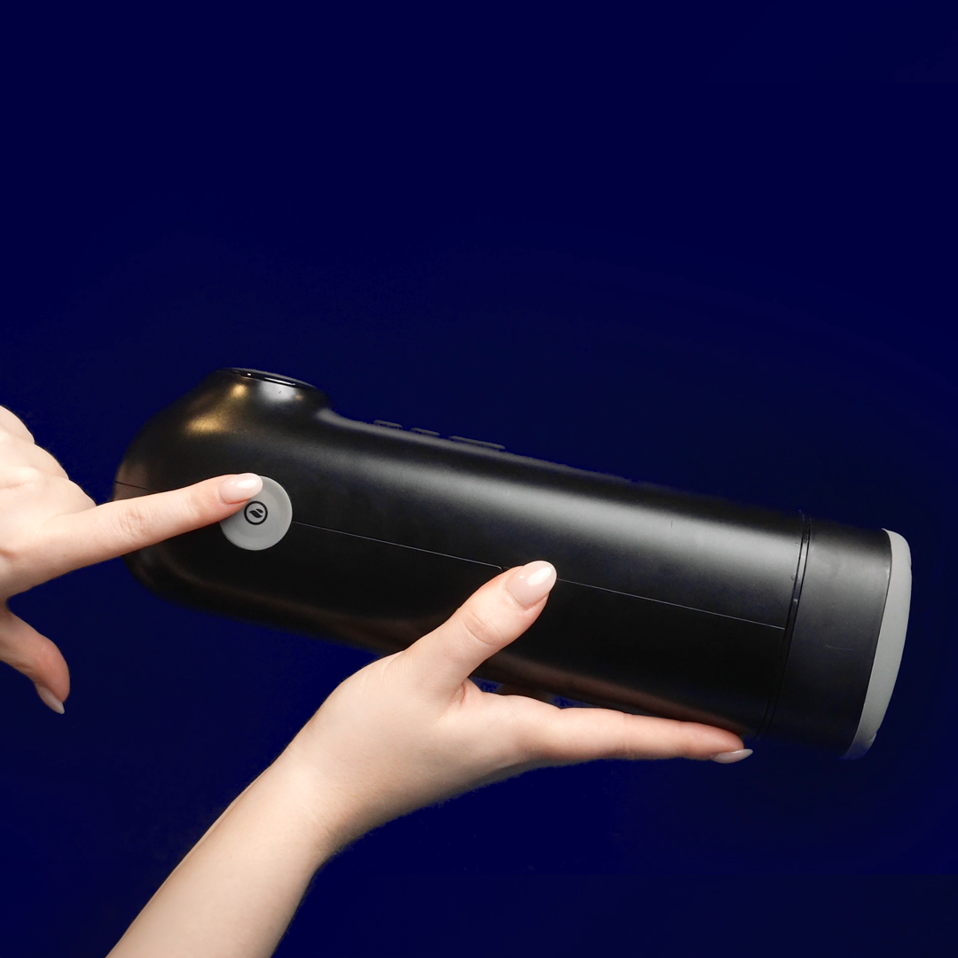 Hands holding and pressing button on a black personal wellness device against blue background.