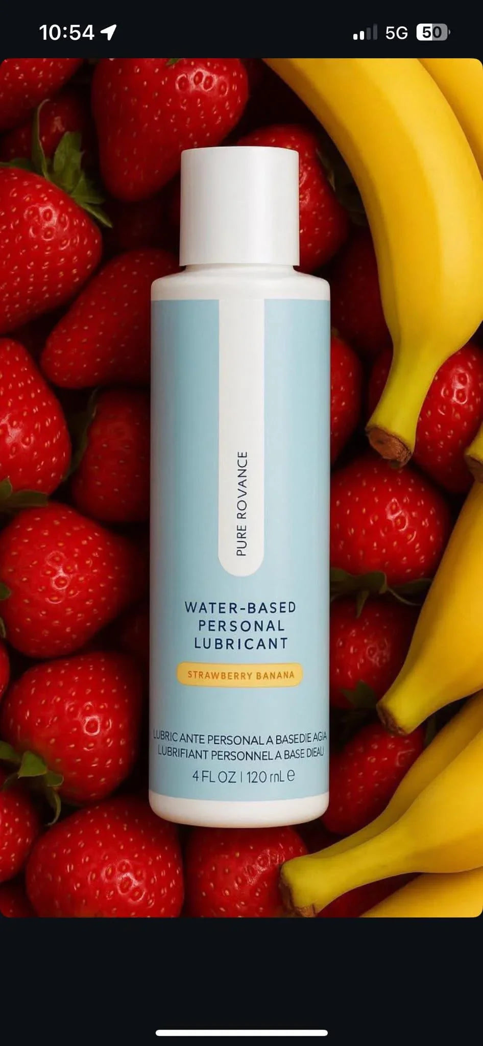 Water-based personal lubricant bottle, strawberry banana flavor, surrounded by strawberries and bananas.