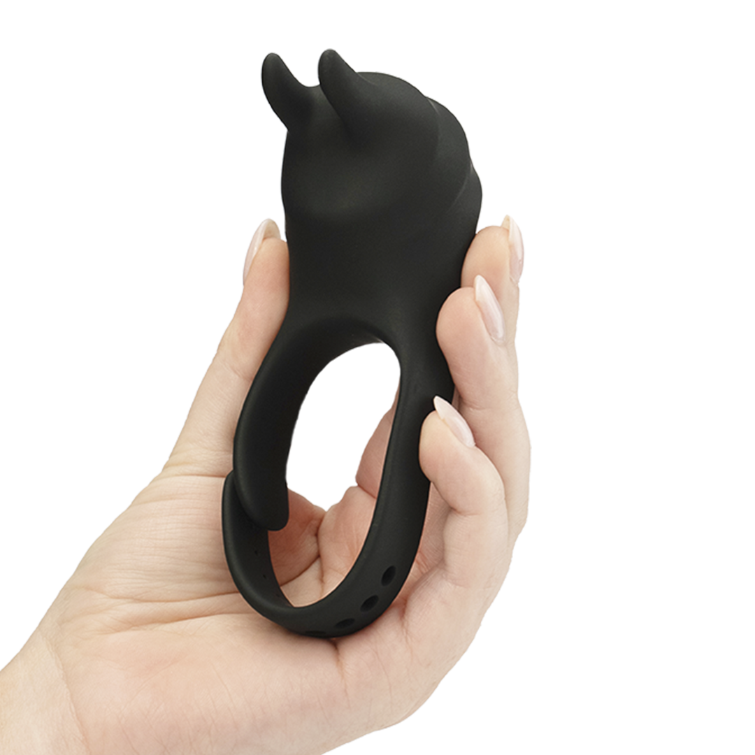 Hand holding a black silicone vibrating ring with bunny ear tips, adult wellness product