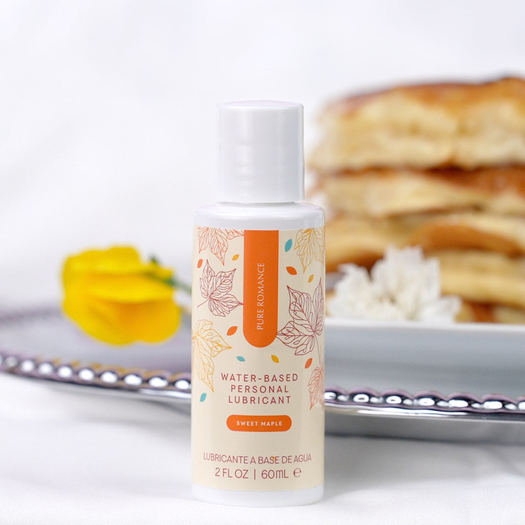 Water-based personal lubricant bottle with maple theme, flower and pancakes in background