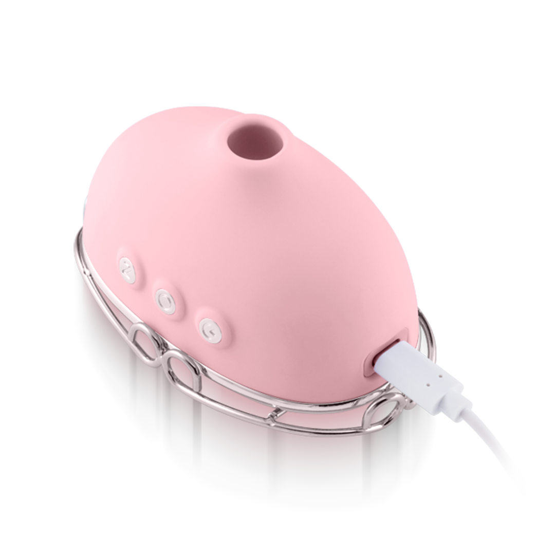 Pink silicone personal massager with buttons and USB charging cable on a metal stand