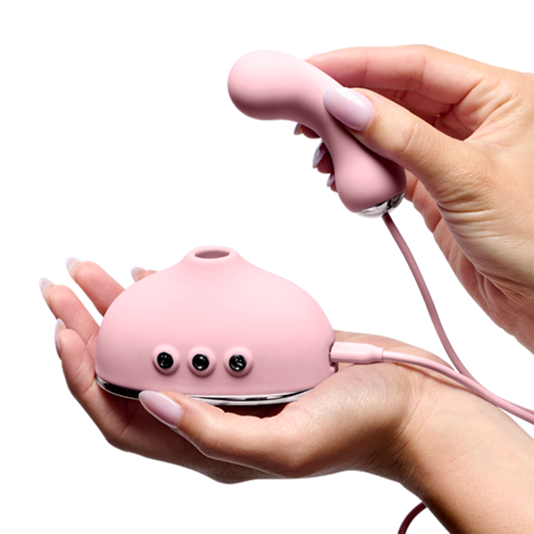 Hands holding a pink silicone wellness massager with control buttons, close-up view
