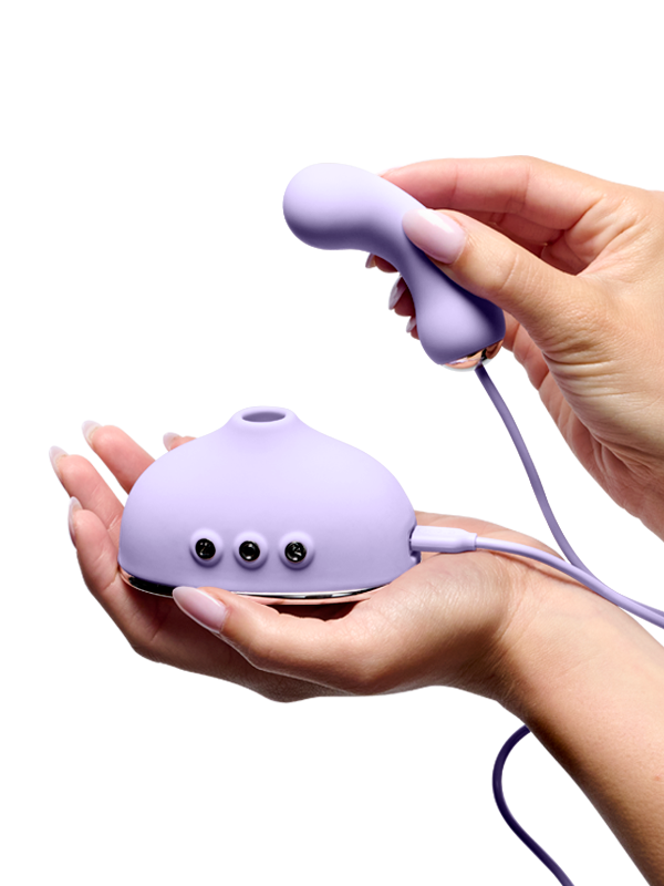 Hands holding a purple silicone wellness massager with control buttons and ergonomic shape
