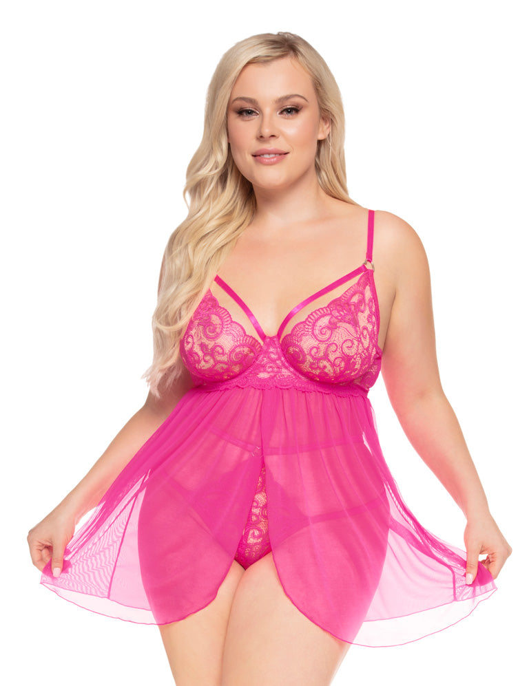 Plus size woman modeling a bright pink sheer lace babydoll lingerie set with strappy details