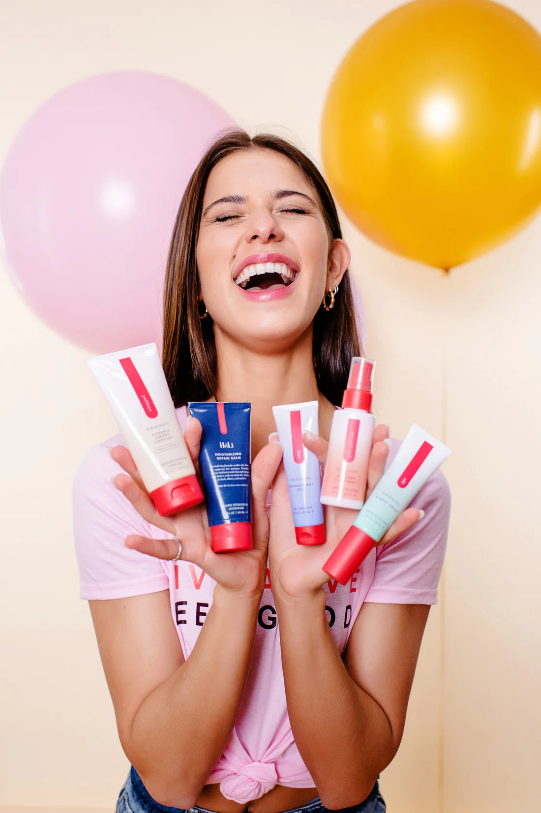Smiling woman holding colorful skincare products with balloons in background